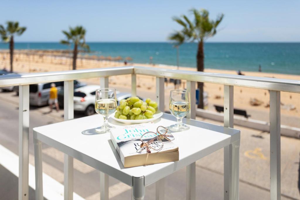 奎特里拉Stunning Studio with Beach Front- Astro Quarteira by Centralgarve的一张桌子,上面有一盘水果和酒杯,放在沙滩上