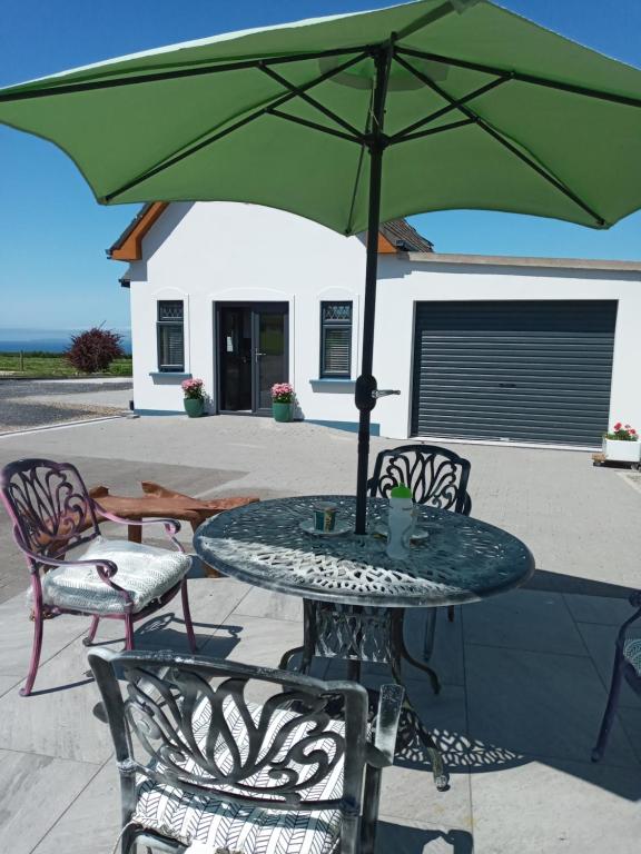 特拉利Luxury holiday rental with sea views on the Wild Atlantic Way的露台上的一张带绿伞的桌子