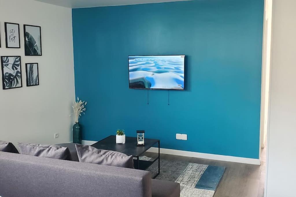 OsnyTulsa Home - Appartement 2 chambres, Charmant et moderne avec terrasse privée的带沙发和蓝色墙壁的客厅