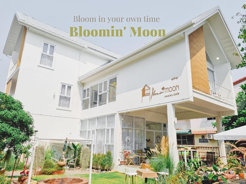 清迈Bloomin' Moon hostel & cafe, Chiang Mai Old Town的白色的建筑,上面有标志,上面写着你自己时间花朵的花朵