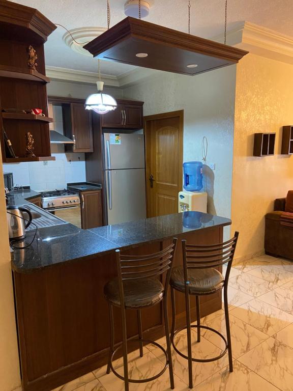 安曼شقة مفروشة للايجار في عمان شارع الجامعة الاردنية的酒吧内的厨房,配有柜台和两个凳子