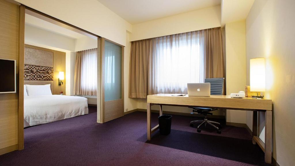 台北福华国际文教会馆的酒店客房配有书桌和床。