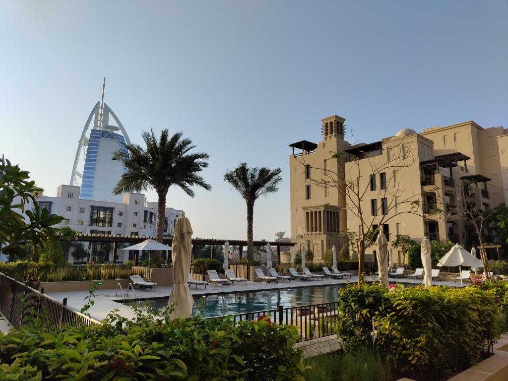 迪拜Ultimate Stay / Next to Burj Al Arab / Upscale Luxury / Amazing Pool with a View / Perfect Holiday / Madinat Jumeirah / 2 BDR的一个带游泳池、建筑和遮阳伞的度假村