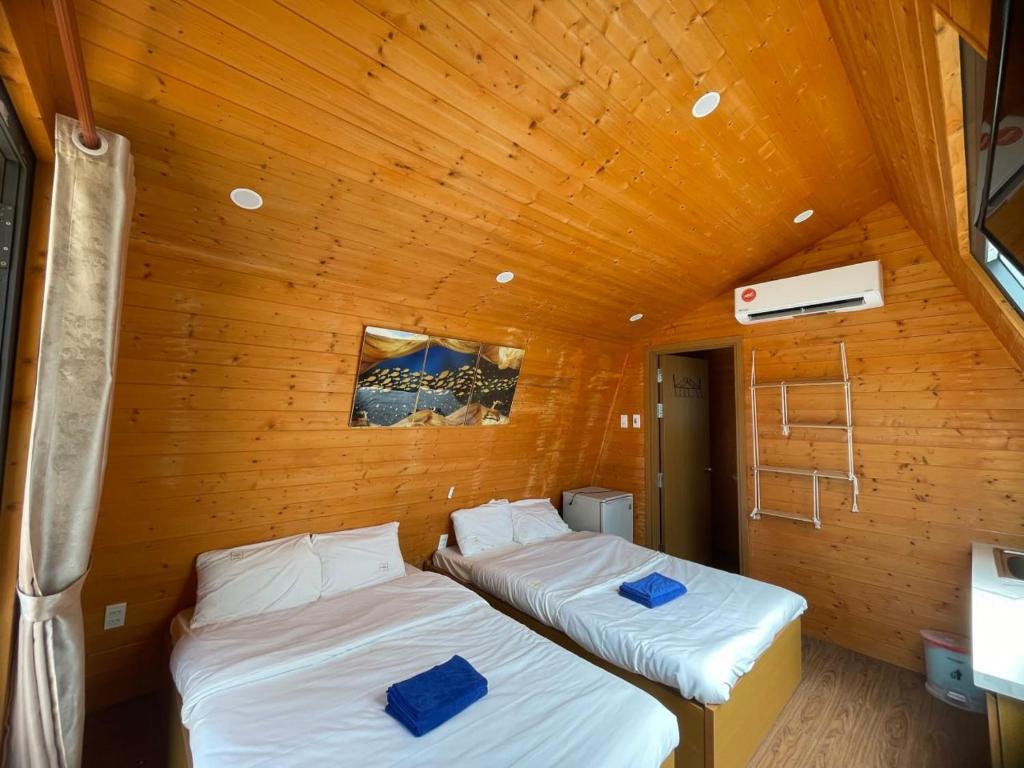 嘎那角Tân Thành Resort的配有木天花板的客房内的两张床
