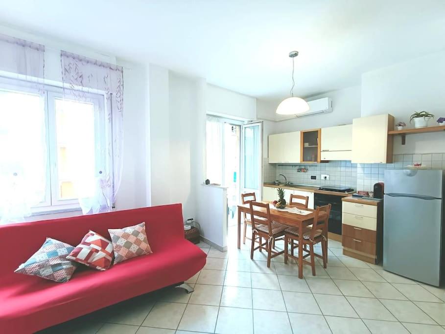 斯培西亚Casa SOFIA La Spezia的一间带红色沙发的客厅和一间厨房