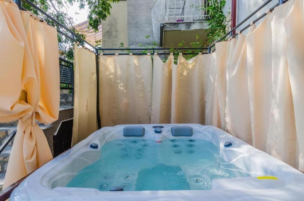 德拉马利Apartman Draga的庭院内的按摩浴缸,配有窗帘