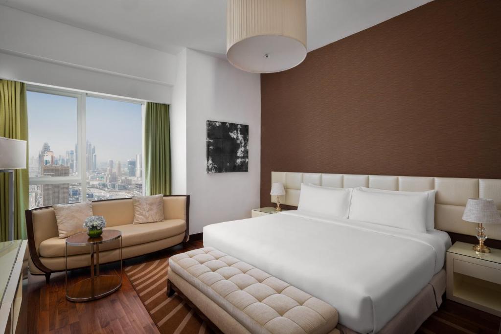 迪拜La Suite Dubai Hotel & Apartments的卧室配有一张白色的大床和一张沙发。