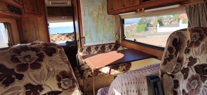 阿德耶Van with 3 double bed, nice and quite place, to 500m beatufill beach的火车室配有椅子、桌子和窗户