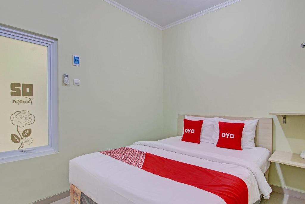 三宝垄OYO 92642 Tumesa Homestay 2 Syariah的一间卧室配有一张带两个红色枕头的床