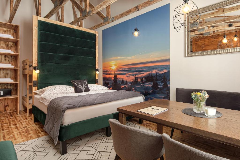 哈拉霍夫Mumlava Resort Harrachov的一间卧室配有一张带绿色床头板的床和一张桌子