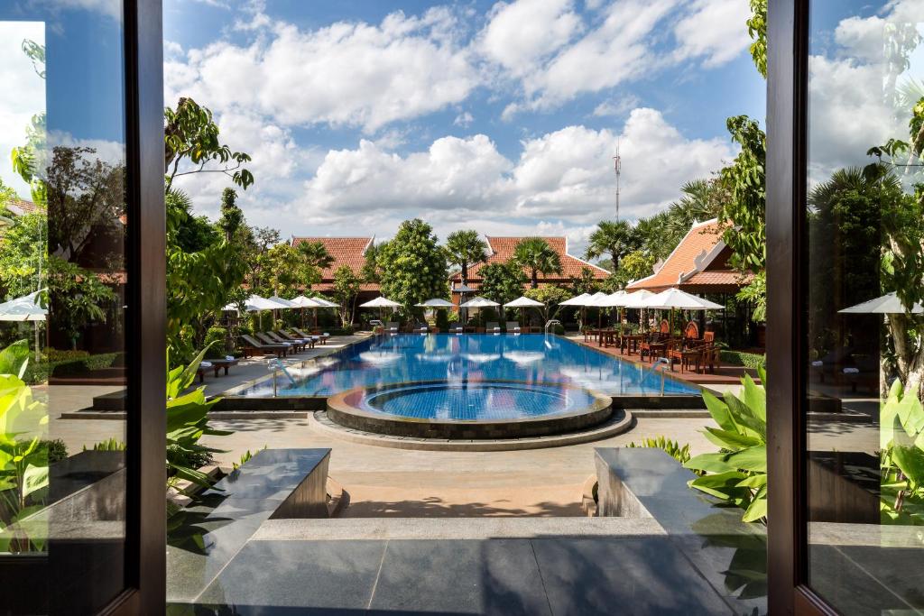 暹粒Angkor Privilege Resort & Spa的享有带桌子和遮阳伞的度假村游泳池的景色