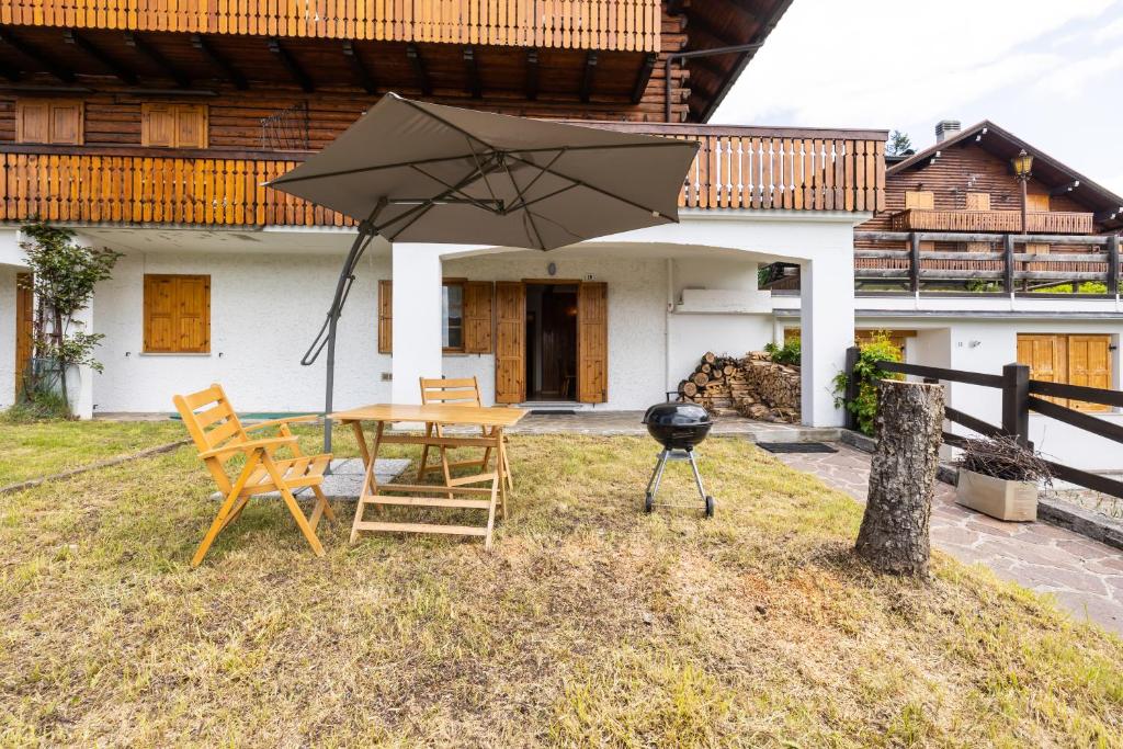 福尔加里亚Grazioso trilocale nel cuore di Folgaria的庭院配有桌椅和遮阳伞。