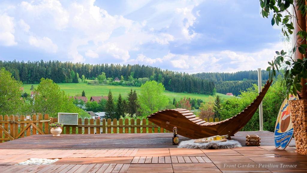 UnterkirnachEntire House in Schwarzwald with mountain view, private Sauna, Gym, Garden and Terraces的庭院里设有一张大型木制吊床,配有围栏