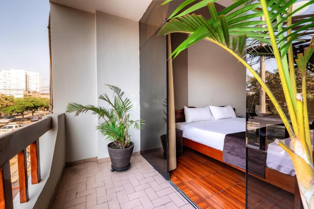 特鲁希略Hotel Portada Del Sol的卧室设有一张位于植物阳台的床铺