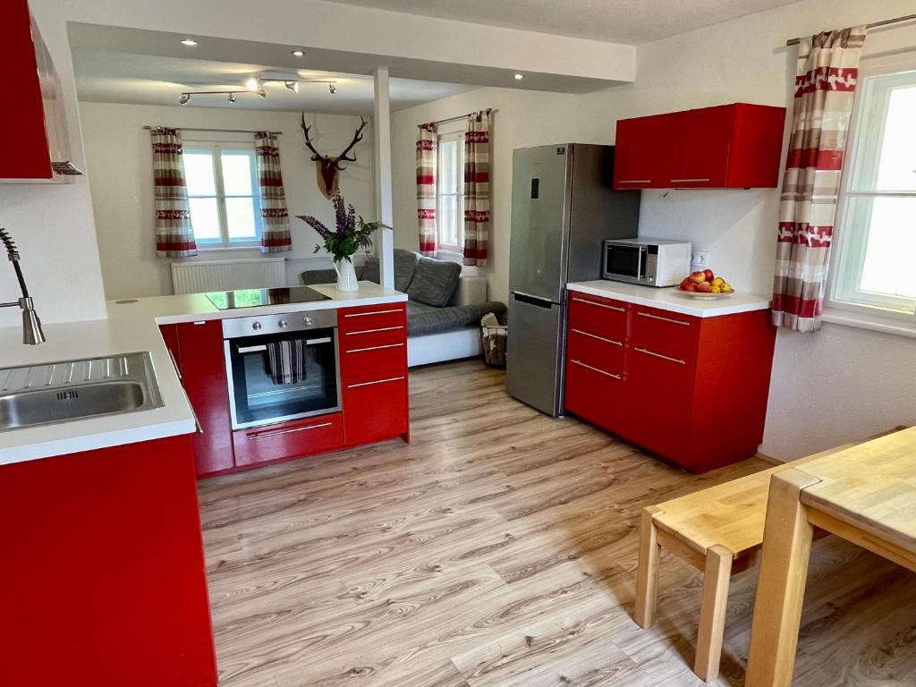 费尔德基兴Lendorfer Cottage的一间厨房,里面配有红色橱柜和一张桌子
