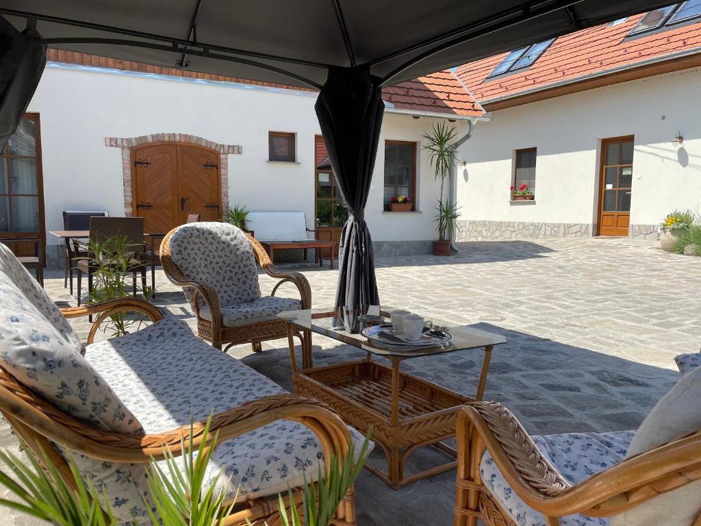 DunabogdányKis-Duna Vendégház的庭院配有椅子和桌子及遮阳伞