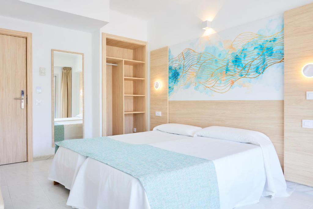 卡拉纳雅达Hostal Gami Adults Only的卧室配有白色的床和墙上的绘画作品