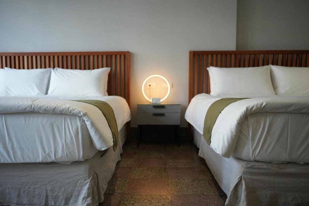 台南璿旅店的床头柜上灯的两张床