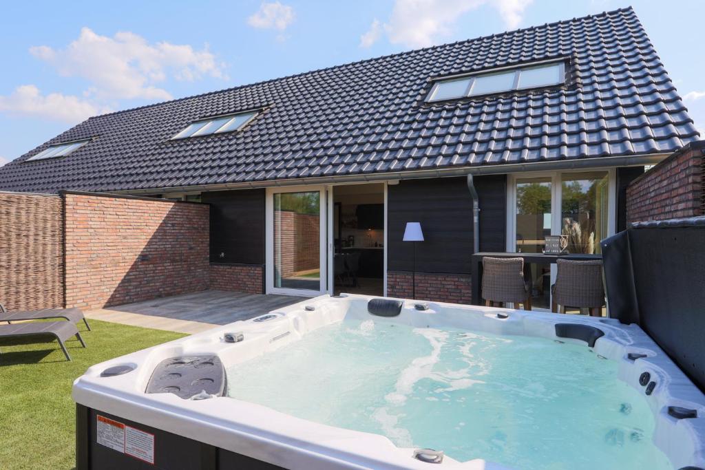 WeerseloErve Mulder vakantiehuis met eigen jacuzzi en eigen sauna的房屋后院的热水浴池