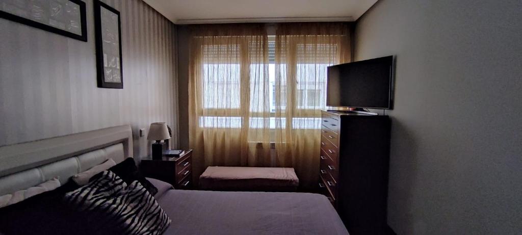 桑托尼亚APARTAMENTO 2 HABITACIÓNES con GARAJE EN SANTOÑA的酒店客房,配有床和电视