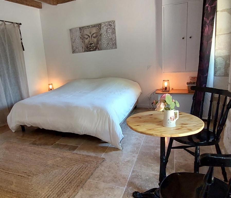 Parçay-les-PinsLe Clos des Roses的一间卧室配有一张床和一张木桌