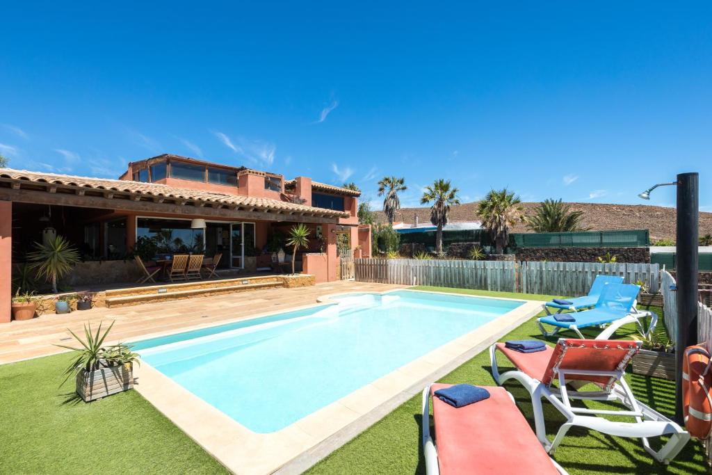 拉奥利瓦Home2Book Ocean Surf House Fuerteventura的一个带椅子的庭院和房子的游泳池