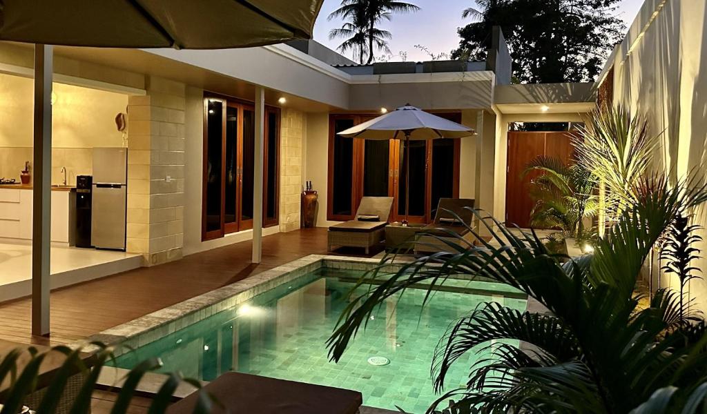 塞隆贝拉纳克Pandan Villas的一座带遮阳伞的别墅内的游泳池