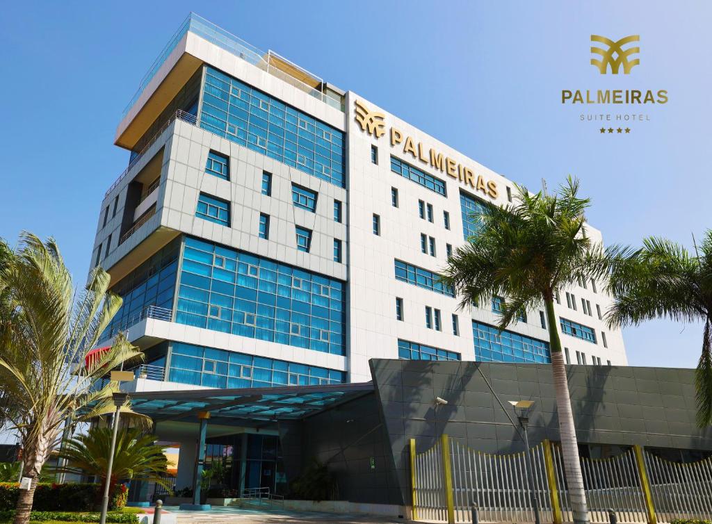 罗安达帕尔梅拉斯套房酒店的前面有棕榈树的建筑