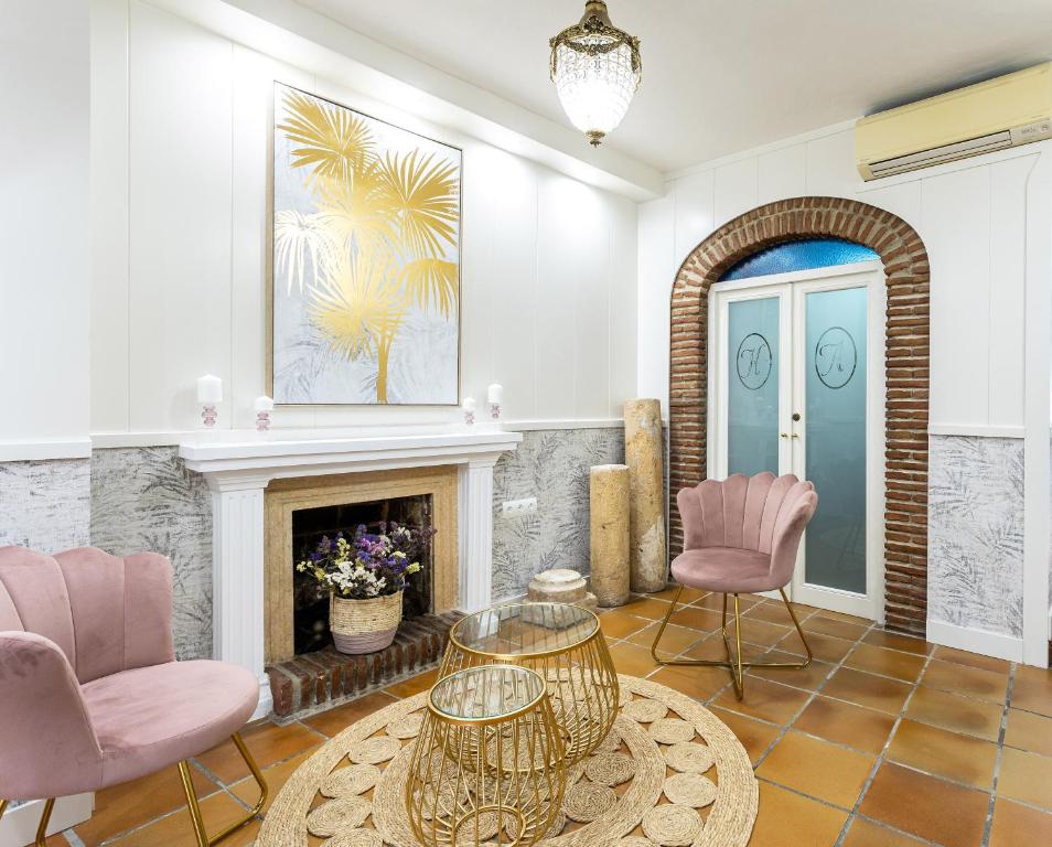马贝拉阿杜瓦雷斯之门酒店的客厅配有粉红色的椅子和壁炉