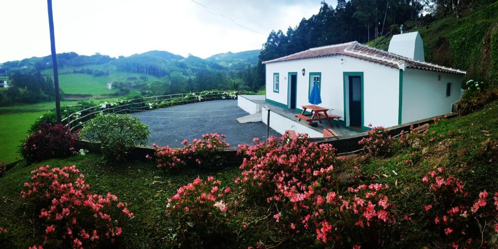 Santo EspíritoCasa dos Valentes的一座小白色房子,位于山上,种着鲜花