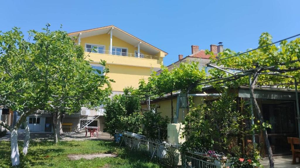 拉夫达стаи за гости Росица的前面有树木的黄色房子