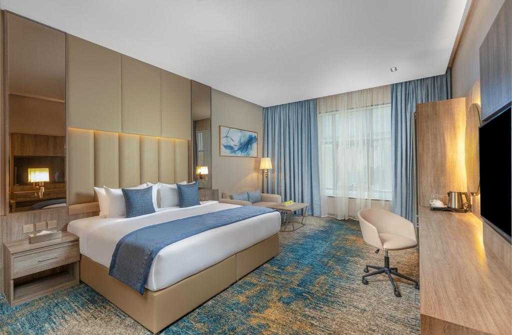 利雅德Seven Gardens Hotel的酒店客房设有一张大床和一张书桌。