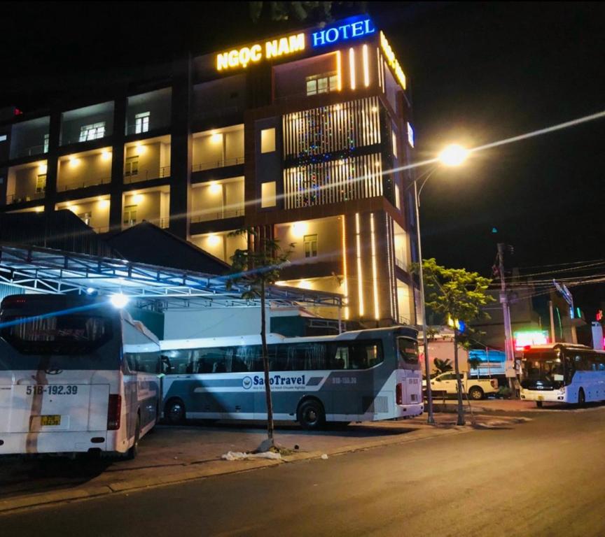 罗夷Ngọc Nam Hotel的夜间停在酒店门前的两辆巴士