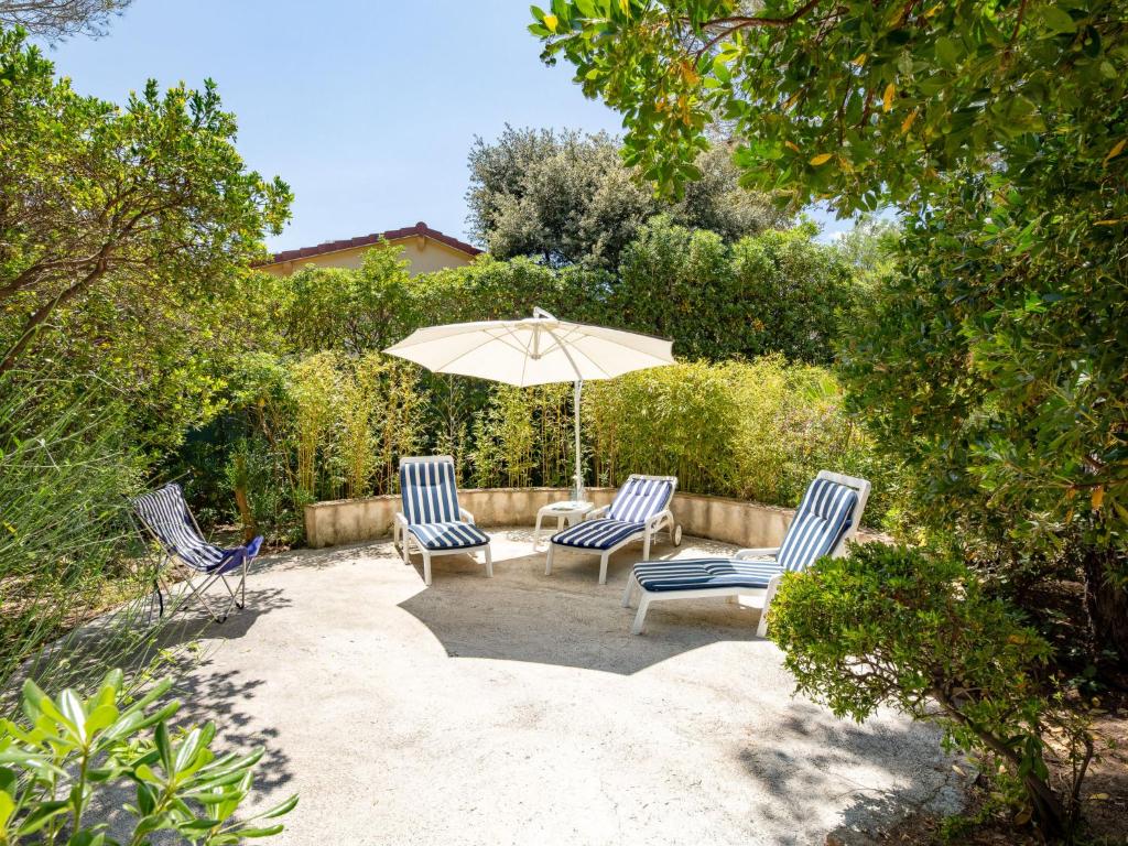 圣艾格夫Villa Les Dauphins by Interhome的庭院配有两把椅子和一把遮阳伞