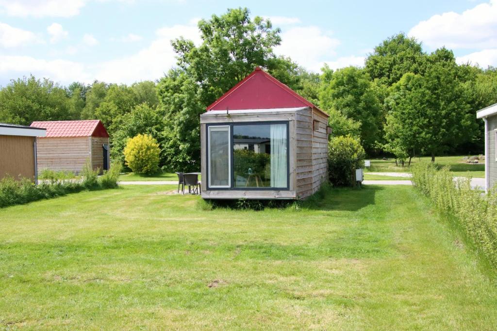 DrijberTiny Cottage op Camping "De stal"的院子中一座红色屋顶的小房子