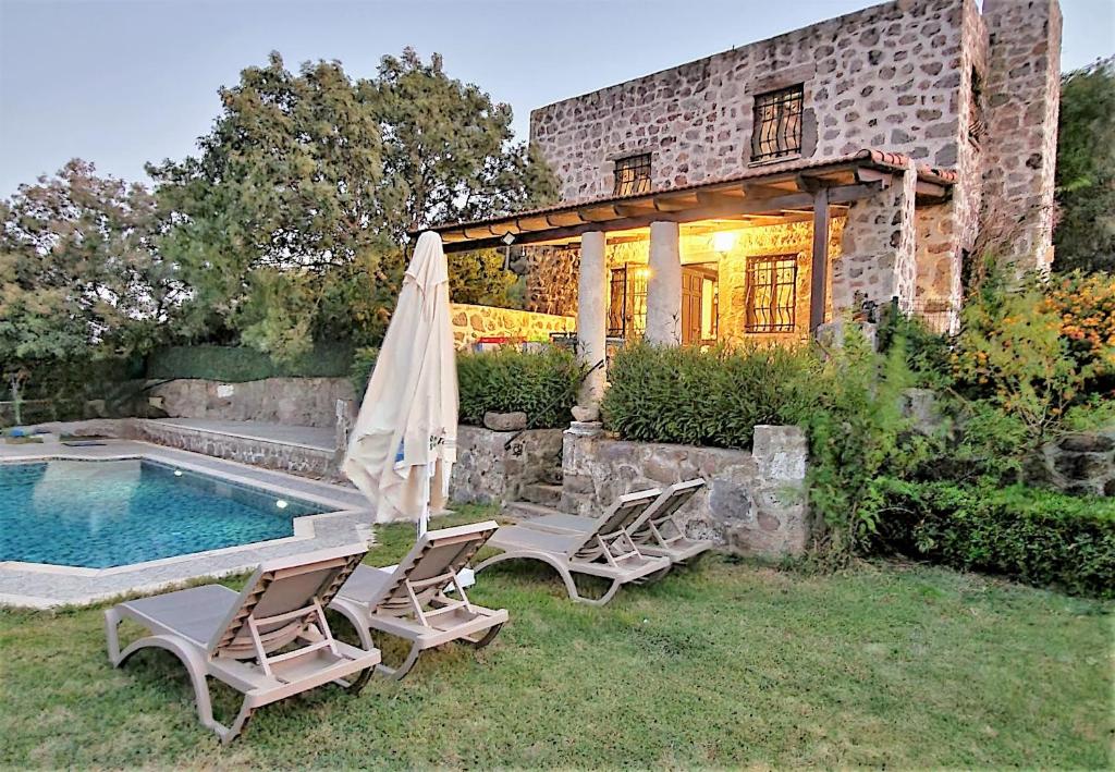 奥塔肯特Authentic Bodrum Villa with Special Private Pool的一座带游泳池、两把椅子和一把遮阳伞的房子