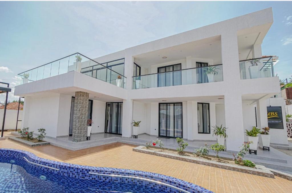 基加利Ibi Villa Retreat的一座大型白色房子,前面设有一个游泳池