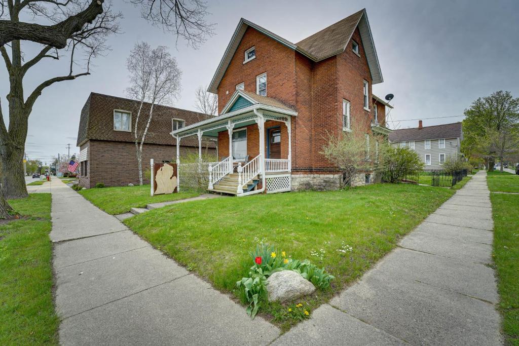 马尼斯蒂Dtwn Victorian Home - 1 Mi to Lake Michigan Beach!的一座带草地庭院的大型砖屋