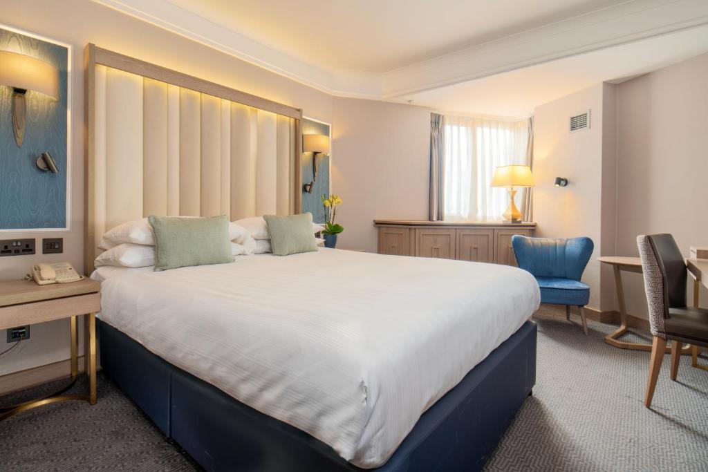 伦敦丹乌比斯摄政公园酒店的酒店客房设有一张大床和一张书桌。