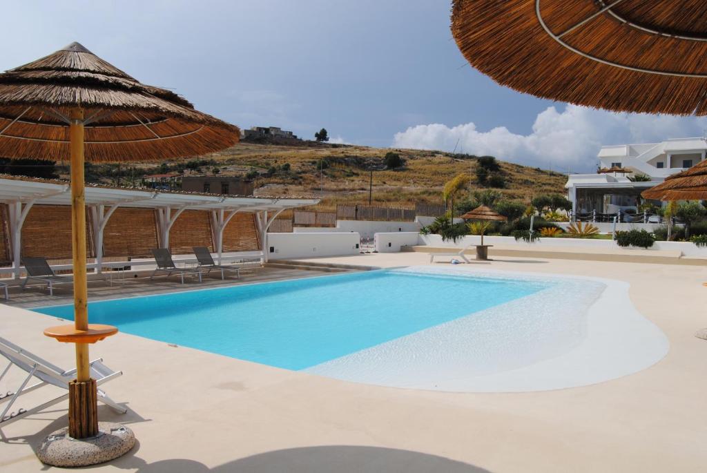 杰拉Villa Aries - Rural Chic Experience的一个带遮阳伞的游泳池以及度假村