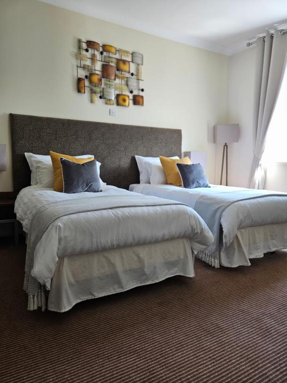 ComptonThe swan at compton的两张位于酒店客房的床,配有蓝色和黄色枕头