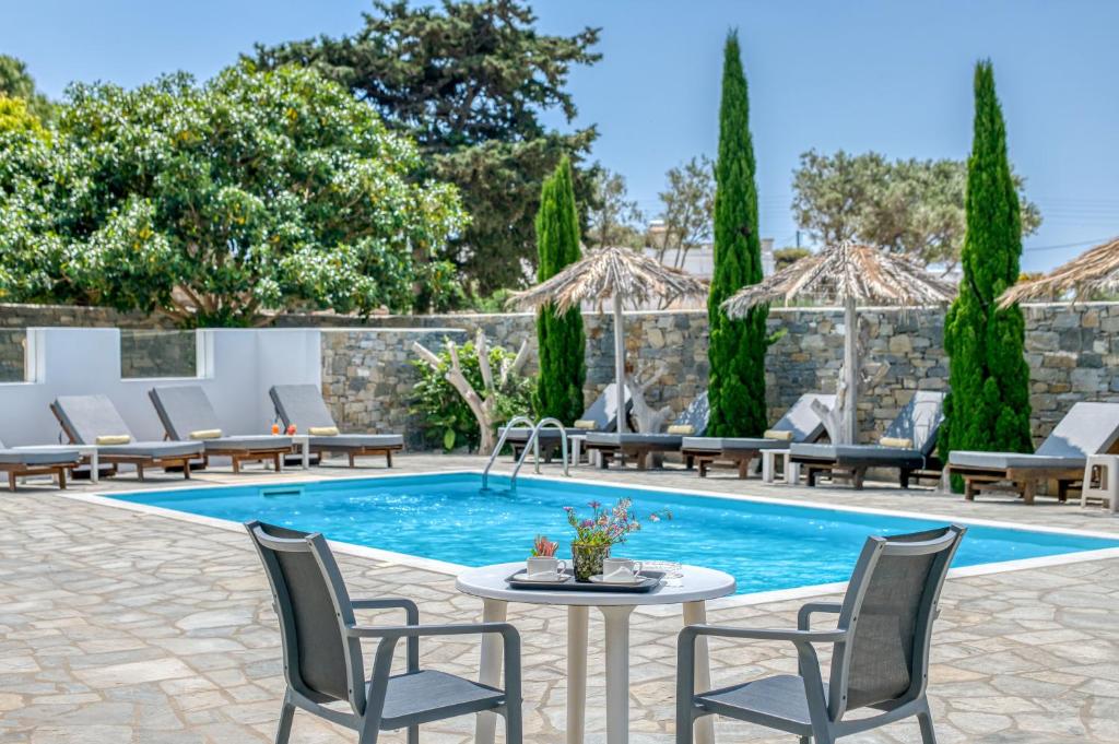 艾丽奇Dahlia Apartments And Studios的庭院设有游泳池、椅子和桌子。