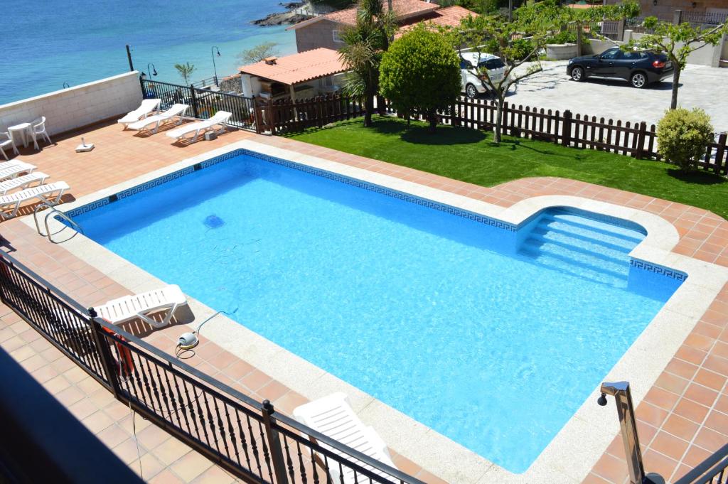 拉科萨Apartamentos Sinás Playa的一个带椅子和庭院的大型游泳池