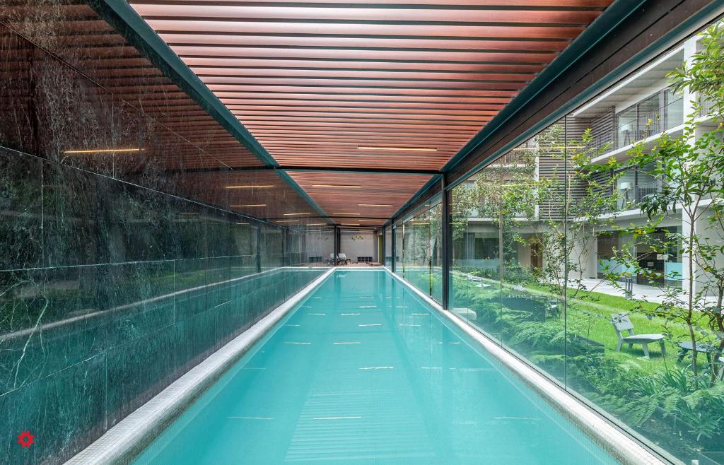 墨西哥城Casa Taman by Kukun的一座带木制天花板的建筑中的室内游泳池