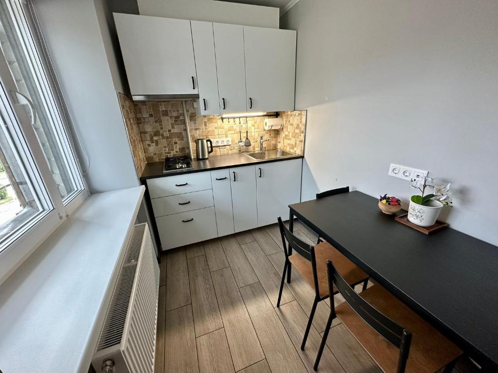 古尔贝内Swan City Family Apartment的厨房配有白色橱柜和黑色桌椅