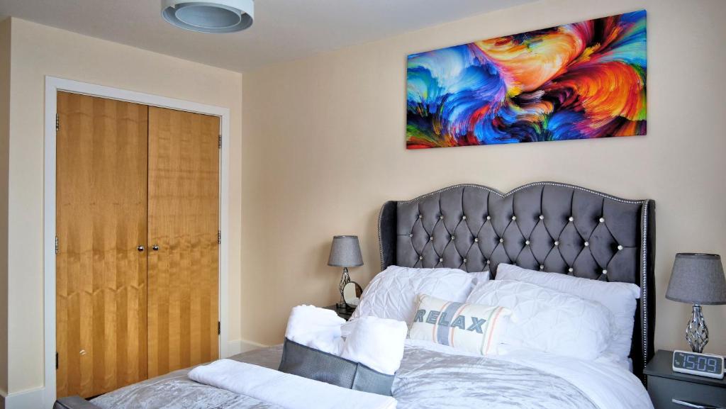 米尔顿凯恩斯Keniji Luxury 2 Bed Apartment的卧室配有一张床,墙上挂有绘画作品