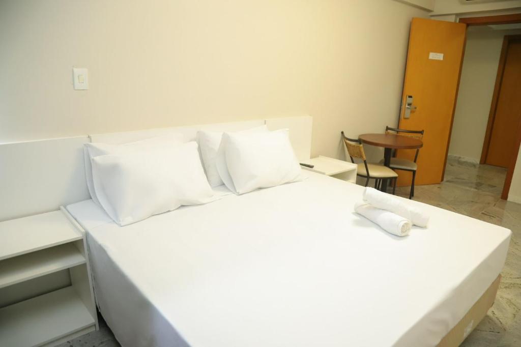 贝洛奥里藏特Rede Andrade Pampulha的白色的床、白色枕头和桌子