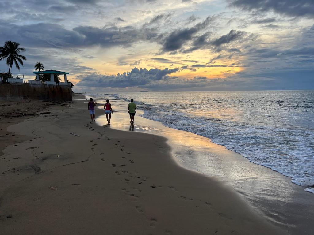 阿瓜达Aguada Beach Condos的两人在日落时分在海滩上散步
