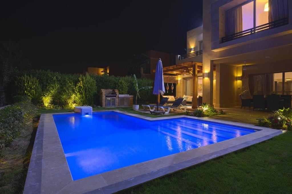 艾因苏赫纳Safty Palm Oasis Private Pool & Beach Access的夜间在房子前面的游泳池