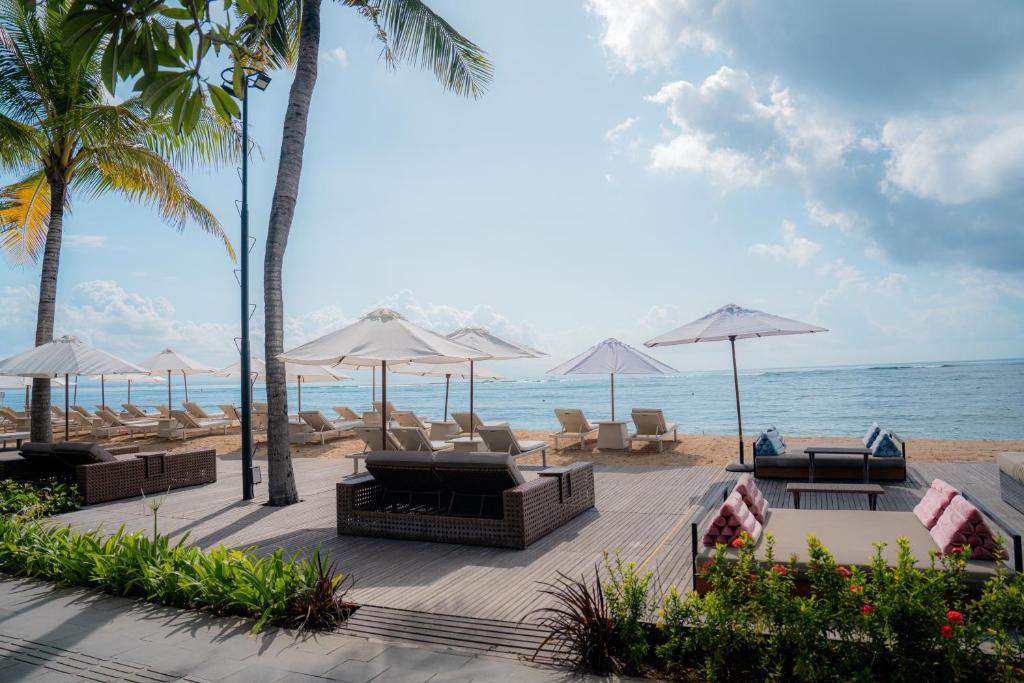 沙努尔格莱亚桑川海滩度假酒店的海滩上设有椅子和遮阳伞,还有大海